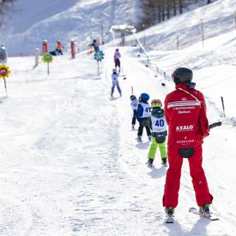 Skilehrer begleitet Kinder auf dem Übungslift in Malbun – ideales Skigebiet für Familien und Einsteiger in Liechtenstein.