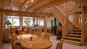 Blick auf den ländlich eingerichteten Gastraum mit runder Treppe und Holzmöbeln