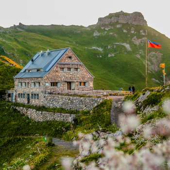 Nahaufnahme der Pfälzerhütte mit Liechtenstein-Flagge bei Abendstimmung.
