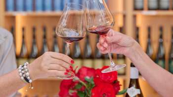 Zwei Personen stossen mit Rotwein in edlen Gläsern der Hofkellerei Liechtenstein an