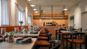 Modern eingerichtetes Restaurant mit offenem Küchenbereich und elegant gedeckten Tischen