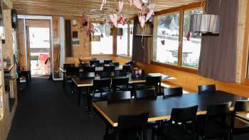 Gemütlicher Gastraum mit Holzwänden, rustikalem Ambiente und liebevoller Dekoration im Restaurant Schneeflucht