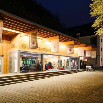 Modernes Besucherzentrum mit Glasfront in Vaduz bei Nacht, einladend beleuchtet.