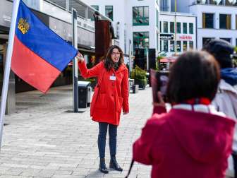 Stadtführerin präsentiert die Flagge Liechtensteins bei einer geführten Tour durch das Zentrum von Vaduz