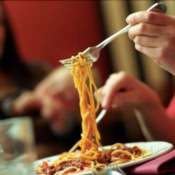 Person hebt mit der Gabel Spaghetti von einem Teller in der Brasserie Burg – italienischer Genuss in geselliger Atmosphäre.