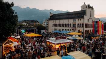 Das Rathaus Vaduz bei Dämmerung mit Lichterketten, spielenden Kindern auf einem Tischtennistisch und sommerlicher Atmosphäre am Staatsfeiertag