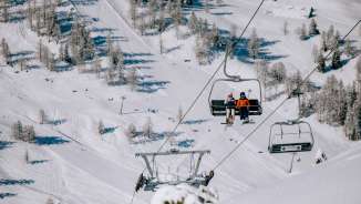 Zwei Skifahrer sitzen im Sessellift über dem verschneiten Skigebiet Malbun in Liechtenstein