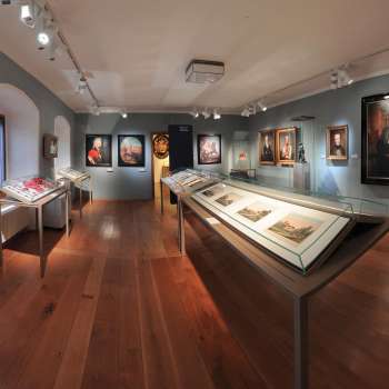 Panoramablick in einen Ausstellungsraum des Landesmuseums mit historischen Gemälden und Schaukästen.
