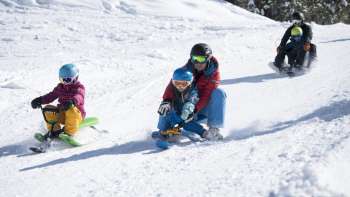 Familienfreundlicher Rodelspaß auf der verschneiten Rodelbahn in Malbun – Kinder und Erwachsene genießen die Abfahrt im Winterparadies Liechtensteins.
