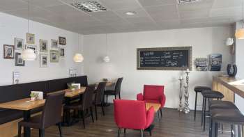  Gemütliches Café mit modernen Sitzmöbeln, dekorativer Bilderwand und warmem Holzboden