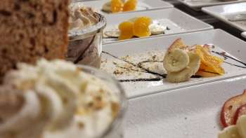 Reich gedeckter Tisch mit kleinen Dessertgläsern, Obst und Garnitur für ein süßes Buffet