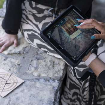 Spielerin verwendet iPad zur Rätsellösung im Outdoor Adventure Room in Malbun.