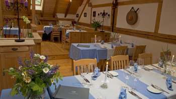 Blau-weiss eingedeckte Tische mit Blumen und Geschirr in einem traditionell dekorierten Raum