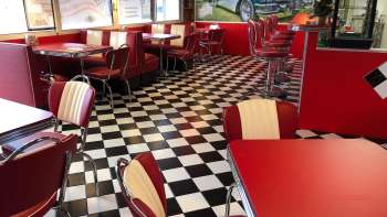 Innenraum des 1950 American Diner mir roten Tischen und schwarz-weissem Boden
