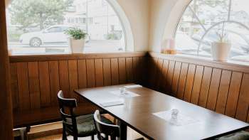 Einladender Gastraum mit hellen Fenstern und rustikaler Holzeinrichtung