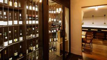 Moderner Weinschrank mit edlen Flaschen in der stilvollen WY Weinbar, Blick in den angrenzenden Verkostungsraum.