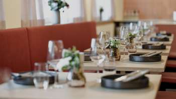 Nahaufnahme stilvoll gedeckter Tische im RUUF Restaurant mit dunklem Geschirr und Blumenvasen