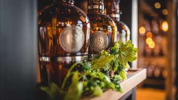 Flaschen mit frisch gezapftem Bier auf sonnendurchfluteter Terrasse, umgeben von lebendiger Stimmung