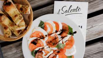 Frische Pizza mit Tomatensauce und Rucola, serviert auf rustikalem Holztisch