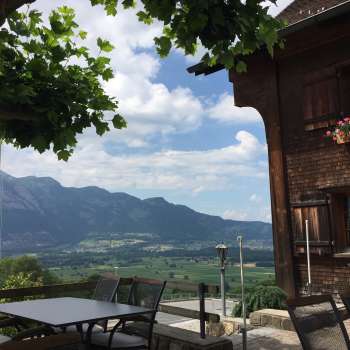 Traditionelles Gebäude mit sonniger Terrasse und Bergpanorama im Hintergrund
