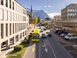 Ein LIEmobil-Bus fährt durch Vaduz vor der Kulisse der Alpen und moderner Architektur