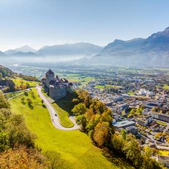 Luftaufnahme von Schloss Vaduz mit Blick über die Stadt Vaduz und das Rheintal an einem klaren Herbsttag