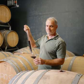 Harry Zech entnimmt Wein zur Verkostung mit einer Pipette aus dem Barriquefass – traditionelle Weinherstellung in Schaan.