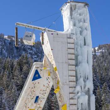 Gefrorener Eisturm in Malbun mit sichtbaren Kletterrouten und Sicherungspunkten, vor blauem Himmel