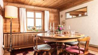 Stilvoll gedeckter Holztisch in einem traditionellen Liechtensteiner Stübli mit Bergblick durch das Fenster