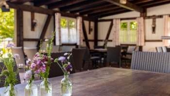 Gemütliche Terrasse mit Holzmöbeln und liebevoller Blumendekoration in Gläsern