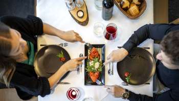 Eine Nahaufnahme eines Tellers mit Mozzarella, Tomaten und Basilikum, dekoriert mit Wein und Kerzenlicht. Eine Nahaufnahme eines Tellers mit Mozzarella, Tomaten und Basilikum, dekoriert mit Wein und Kerzenlicht.