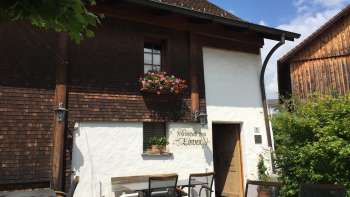 Rustikales Gasthaus mit Holzfassade und blumengeschmückten Fenstern