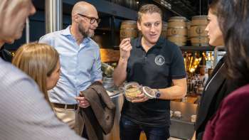 Ein Mitarbeiter erklärt einer Gruppe interessierter Gäste Brauzutaten bei einer Führung durch die Brauerei.