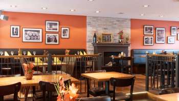 Gemütlicher Gastraum im Restaurant new castle mit warmen Farben, Kamin und stilvollen Holztischen