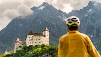 Mountainbiker in gelber Jacke blickt auf die Burg Gutenberg