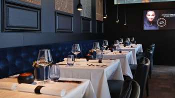 Eleganter Innenbereich des Esquire Bar & Bistro in Vaduz mit stilvoll gedeckten Tischen, dunkelblauer Polsterbank und stimmungsvollem Licht.
