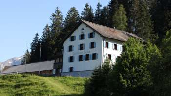 Traditionelles Berggasthaus Sücka inmitten grüner Landschaft und umgeben von Wäldern