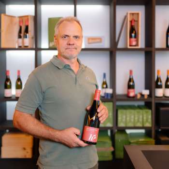Harry Zech präsentiert eine Flasche seines Weins im stilvollen Verkaufsraum – regionale Weinkultur aus Liechtenstein.