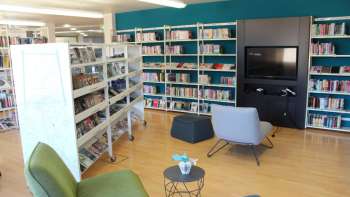 Gemütliche Leseecke in der Liechtensteinischen Landesbibliothek mit Sesseln und Medienwand zwischen hohen Bücherregalen
