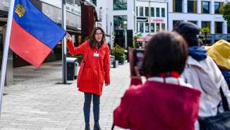 Stadtführerin präsentiert die Flagge Liechtensteins bei einer geführten Tour durch das Zentrum von Vaduz