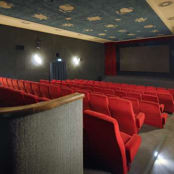 Seitlicher Blick in den Kinosaal des Alten Kino Vaduz mit roten Sesseln und atmosphärischer Beleuchtung.