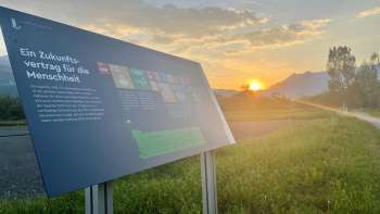 Infotafel zum Ernährungsfeld Vaduz mit Blick auf die Alpen im Sonnenuntergang – ein Lernort zur nachhaltigen Ernährung in Liechtenstein.