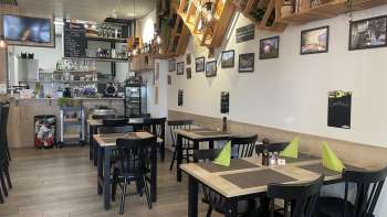 Gemütliches Restaurantinterieur mit modernen Holztischen, grünen Servietten und dekorativen Elementen