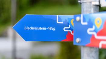 Blauer Wegweiser mit Aufschrift „Liechtenstein-Weg“ in moderner Gestaltung.