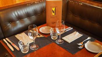 Gedeckter Tisch mit Speisekarte im Leder-Sitzbereich des Vanini Cafés
