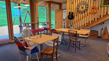 Gemütlicher Gastraum mit Holzelementen – Der Gastraum ist mit hellen Holzmöbeln und dekorativen Gitarren an der Wand gestaltet, warme Atmosphäre durch natürliches Licht.