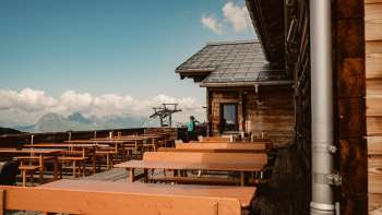Leere Holzbänke auf der Aussichtsterrasse der Sareis-Hütte mit Blick auf die Alpen