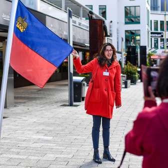 Stadtführerin präsentiert die Flagge Liechtensteins bei einer geführten Tour durch das Zentrum von Vaduz