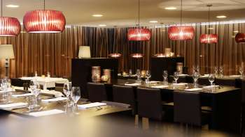 Stilvoller Gastraum mit dunklen Möbeln, roten Designlampen und edlem Ambiente