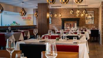 Elegantes Restaurant mit stilvoller Einrichtung, weißen Tischdecken und Kamin für gemütliche Atmosphäre.
